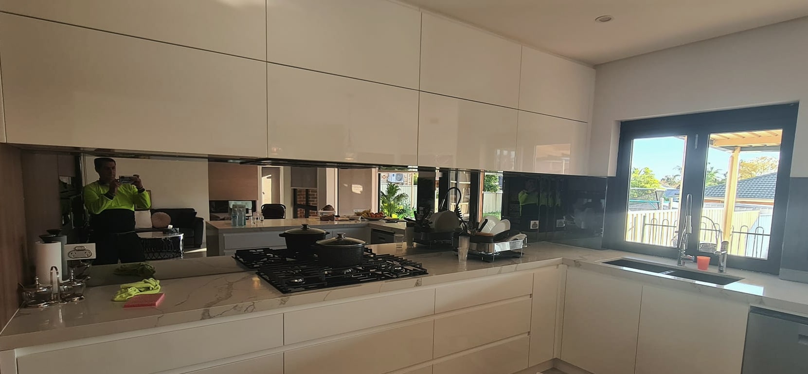 Bronze mirrored and black glass splashback running behind a kitchen cooktop